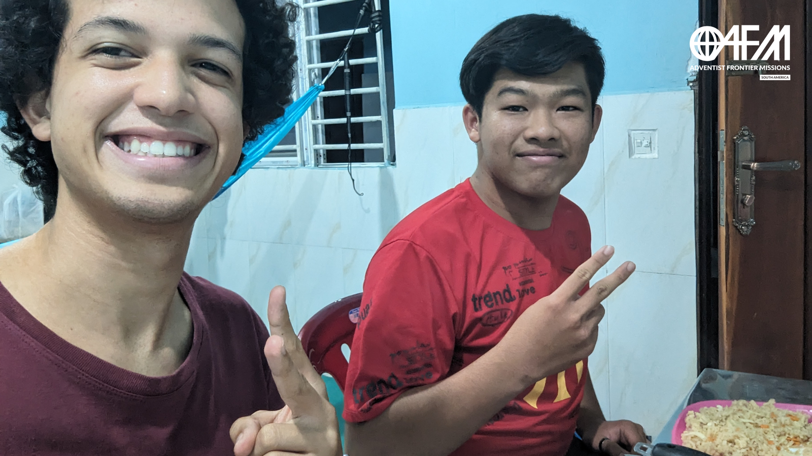 Misionero sonriendo a la cámara con un nativo camboyano antes de cenar en la mesa